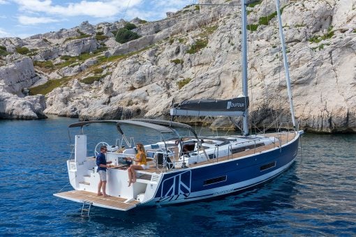 Dufour 530 electric monohull at anchor on sea with couple relaxing