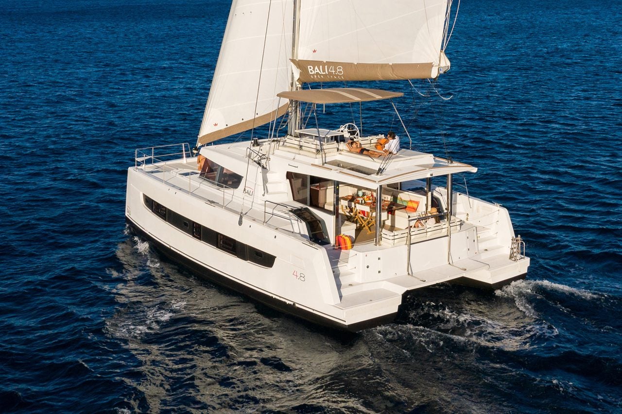 Bali 4.8 sailing catamaran on ocean with couples on deck