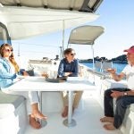 Guest sitting on table on deck of Excess 11 catamaran sailboat