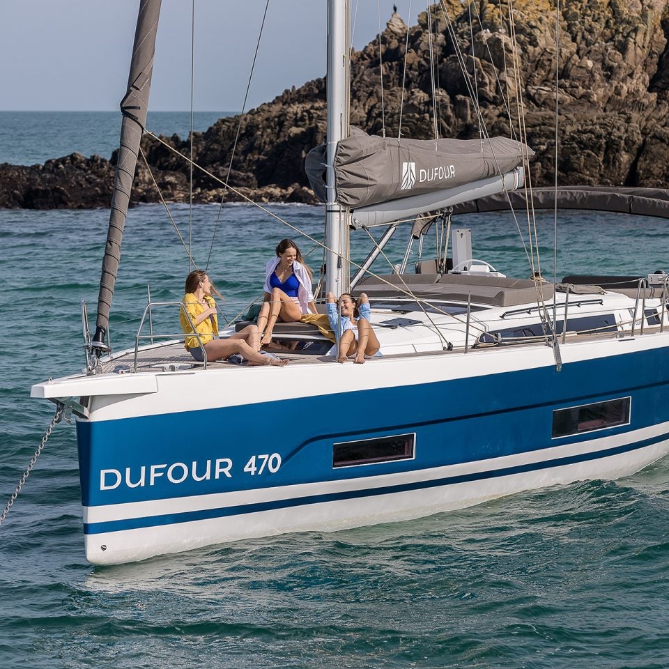 Dufour 470 sailboat at anchor with people on bow