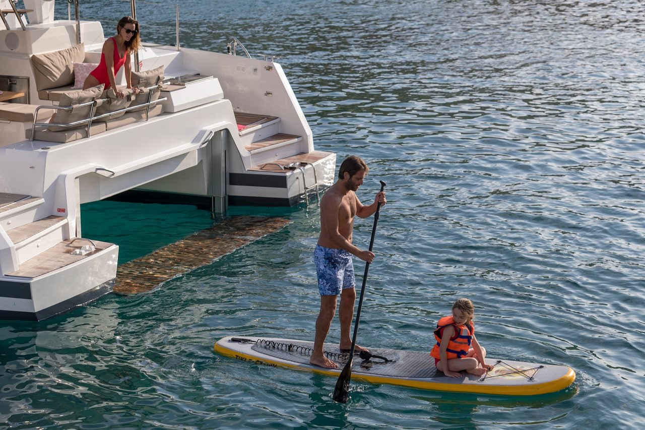 Couple using the Astrea 42 catamaran swim platform for paddleboarding