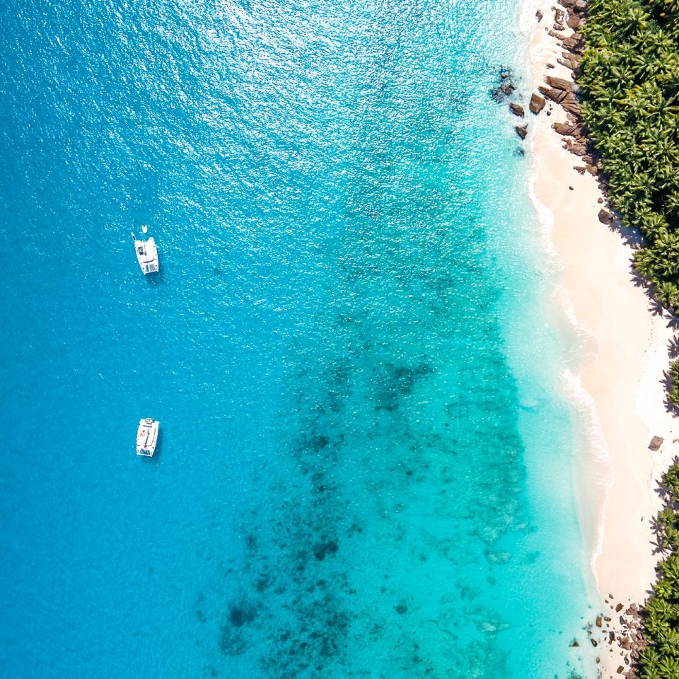 Dream Yacht island destination aerial of beach and two sailing catamarans