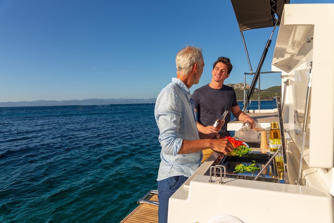 Men using the outdoor grill on the Dufour 61 luxury yacht