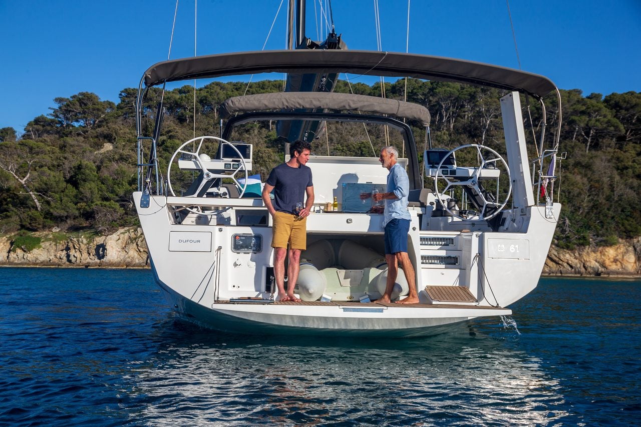 Men using the outdoor transom grill on the Dufour 61 monohull