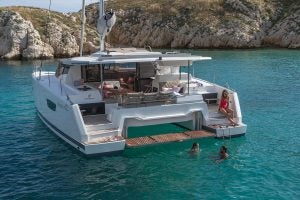 Astrea 42 catamaran smart electric at anchor near rocky coastline