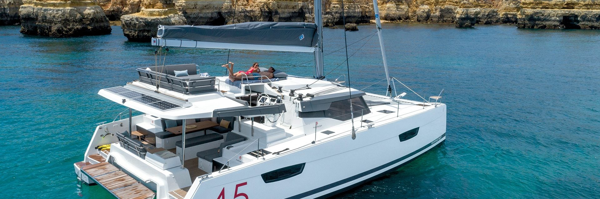 Fountaine Pajot Elba 45 sailing catamaran at anchor near cliffs