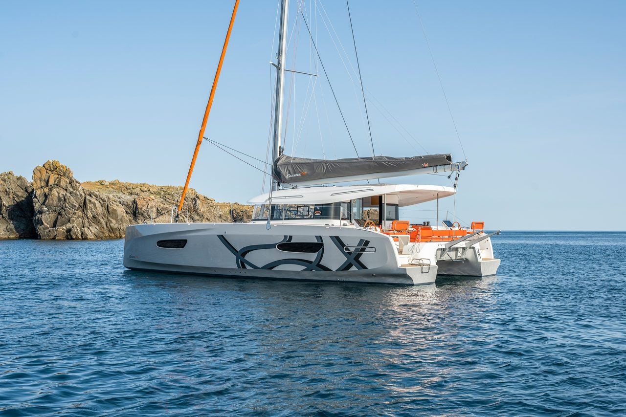 Excess 14 catamaran anchored near a rugged coastline