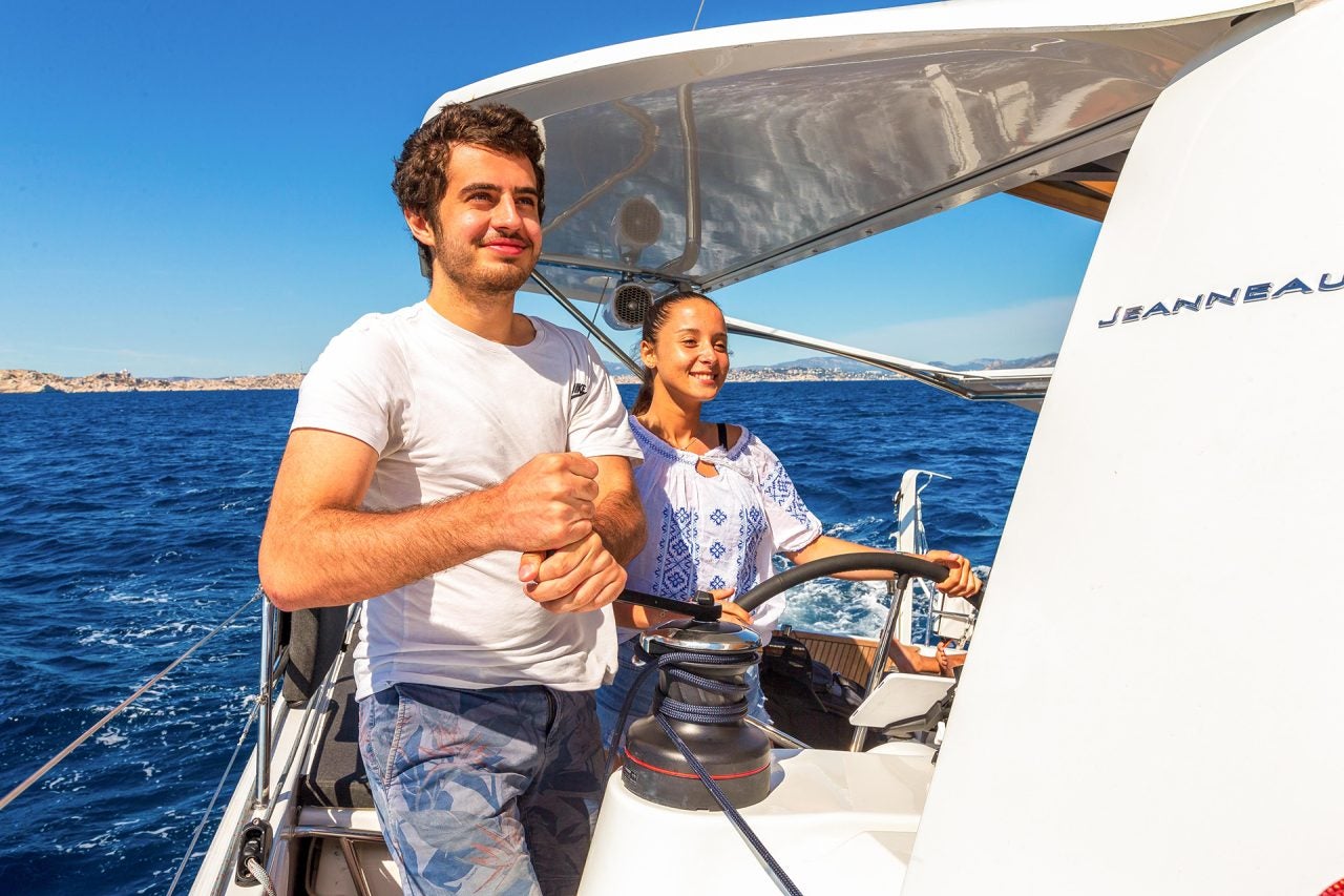 Couple at the helm of the Sun Loft 47 sailboat