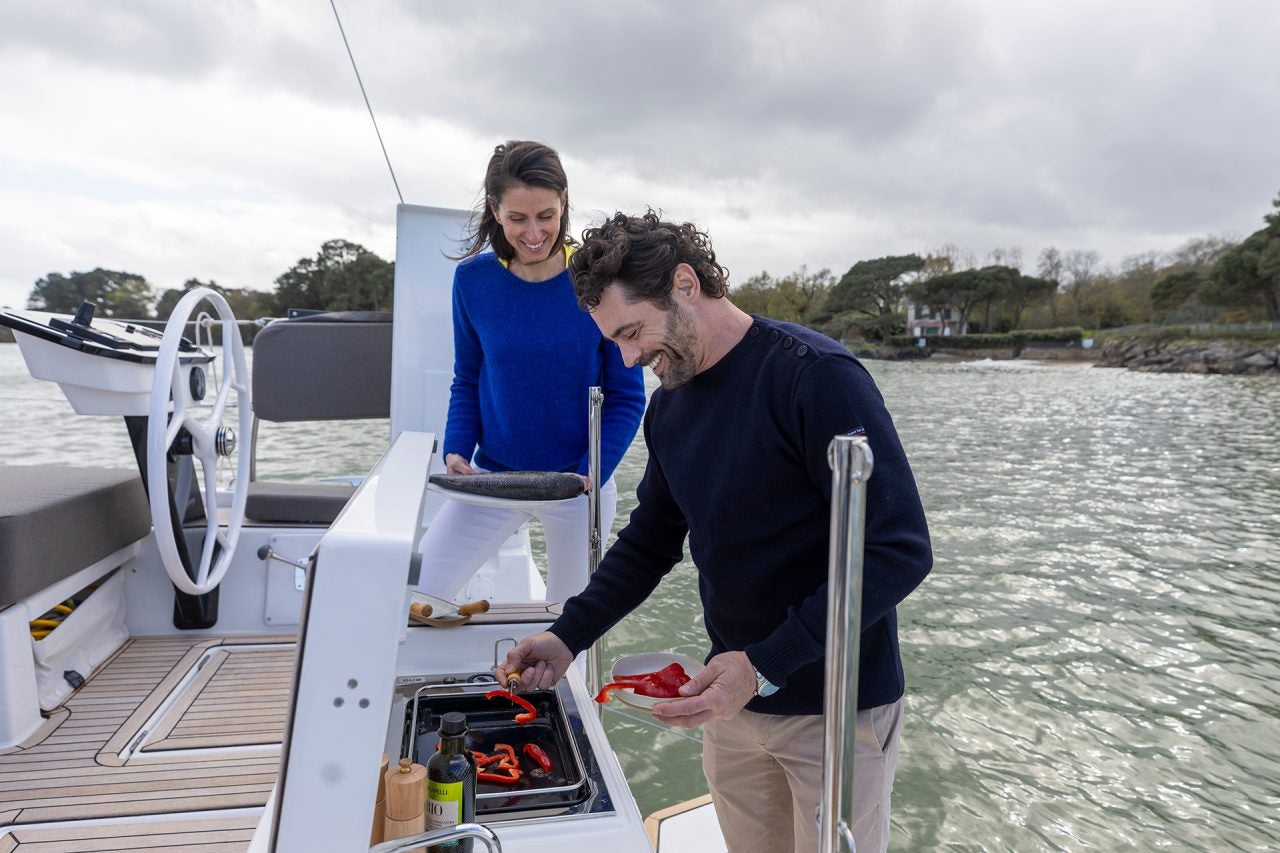 couple using the outdoor transom grill on the Dufour 44 monohull